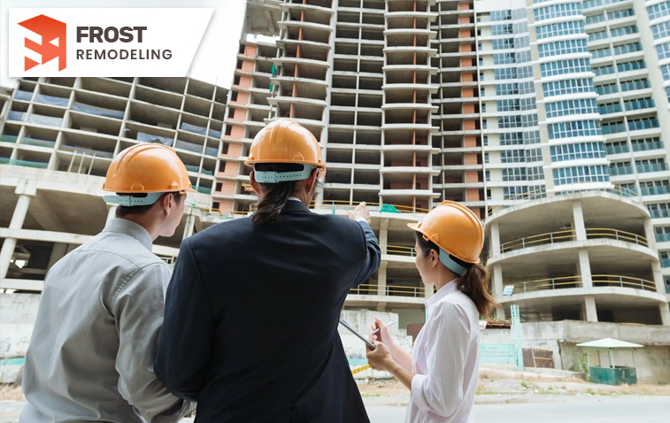 Professional team discussing about construction blueprint in front of a building under construction